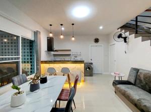 a kitchen and a living room with a table and chairs at Hidden Gems Residence in Ban Sala Daeng