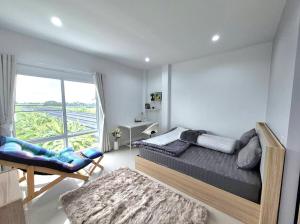 a bedroom with a bed and a chair and a window at Hidden Gems Residence in Ban Sala Daeng