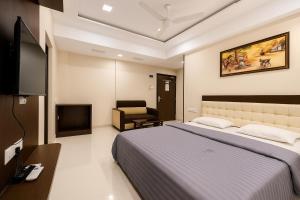 普杰StayGuru Park View Residency的一间带床、电视和椅子的卧室