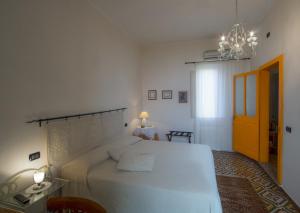 a bedroom with a large white bed and a chandelier at S'Attobiu Guest Rooms in Teulada