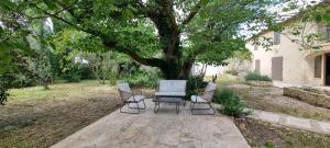 three chairs and a table under a tree at Malicroix in Arles