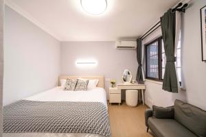 Un dormitorio pequeño con una cama y un sofá. en Downtown, 2BR 1LR 1KT 1BA, near Pedestrian St, the Bund, Pearl Tower, en Shanghái