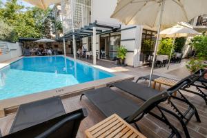 a swimming pool with two chairs and an umbrella at Bayram Hotel in Çeşme