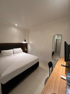 a bedroom with a bed and a desk with a mirror at Hotel Harmony in Batulicin