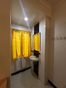 a bathroom with a yellow shower curtain and a sink at Hotel Harmony in Batulicin