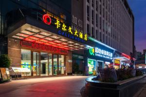 a building with neon signs in a city at night at Calvin International Hotel Guangzhou Sanyuanli Metro Station Branch - Free Shuttle Bus to Canton Fair Complex During Canton Fair Period & Free Deliver Service to Guangzhou Baiyun International Airport in Guangzhou