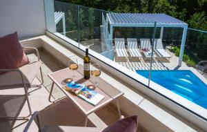 LinardićiにあるAmazing Home In Linardiciのバルコニー(テーブル、ワイングラス、スイミングプール付)