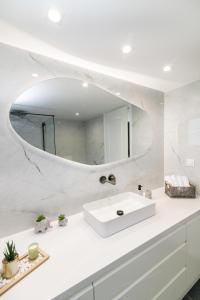 a white bathroom with a sink and a mirror at Windmill Villa in Tinos in Agios Sostis +46 photos