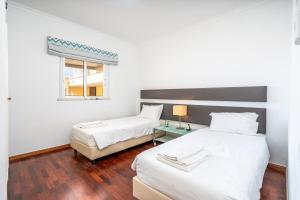 two beds in a white room with a window at Vilamoura Central 2 Bedroom Flat in Vilamoura +10 photos