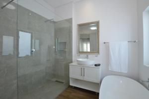 Un baño blanco con lavabo y ducha. en Caracal 54 Overnight for 2, en Yzerfontein