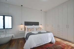 Un dormitorio blanco con una cama y una bañera. en Caracal 54 Overnight for 2, en Yzerfontein 2 fotos más