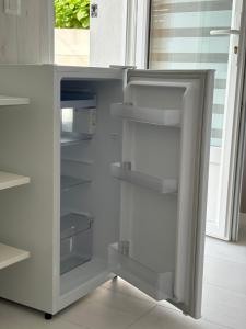 a white refrigerator with empty shelves in a kitchen at Suite indépendante avec piscine proche Océan in Saint-Vincent-de-Tyrosse