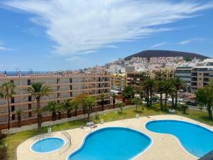 a view of two pools in a city with buildings at Seaside Two Bedroom Apartment in Los Cristianos