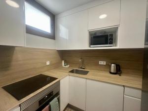 a kitchen with white cabinets and a sink and a microwave at Seaside Two Bedroom Apartment in Los Cristianos