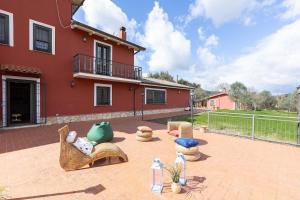 a patio with furniture and a red house at Villa Flo' - Piscina Privata, Relax & Privacy in Manciano