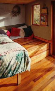 a bedroom with a bed and pillows on a wooden floor at Lime Hut with wood burning sauna - Waipara Narrows in Glasnevin