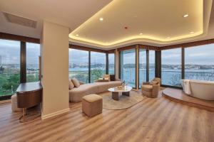 - un salon avec un canapé, une baignoire et des fenêtres dans l'établissement Çırağan Hotel Bosphorus, à Istanbul