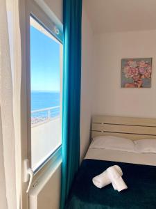a bedroom with a bed and a window with the ocean at Saint Gin Apartment in Shëngjin
