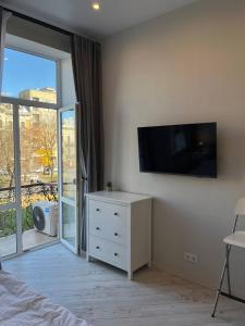 a bedroom with a white dresser and a tv on a wall at Lucky Apartmens in centre Lviv in Lviv