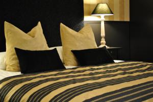 a bed with black and white pillows and a lamp at Domaine De L'espal in Meursac