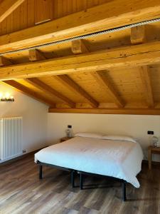 un lit dans une chambre avec des plafonds en bois dans l'établissement Casa Viola, à Ledro