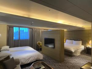 a hotel room with two beds and a flat screen tv at The Landis Taipei in Taipei