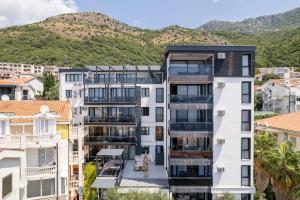 an apartment building with mountains in the background at Olive Apartment in Sveti Stefan