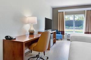a hotel room with a desk with a computer and a bed at Comfort Inn & Suites Orlando North in Sanford
