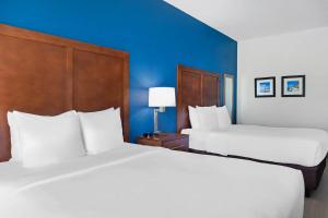 two beds in a hotel room with blue walls at Comfort Inn & Suites Orlando North in Sanford