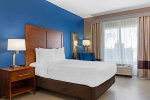 a bedroom with a large bed and a blue wall at Comfort Inn & Suites Orlando North in Sanford