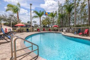 a swimming pool with chairs and umbrellas at a resort at Comfort Inn & Suites Orlando North in Sanford