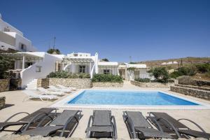 a villa with a swimming pool and lounge chairs at Marvi House Mykonos Holiday Home in Ornos