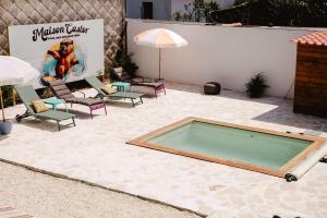 a swimming pool in a patio with chairs and an umbrella at Maison Castor, balnéo et billard chez Ivona Vacances in Mimizan