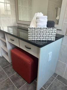 a bathroom with a counter with towels and a red stool at 82 on 21st in Mossel Bay