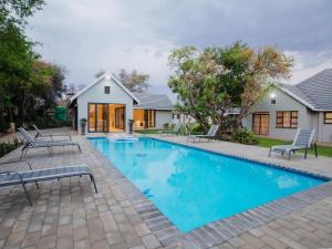 a swimming pool in front of a house at Naledi@53 Private Game Farm in Brits