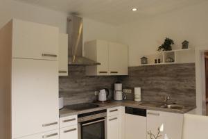 a kitchen with white cabinets and a sink at Apartment Merle in Wimbach