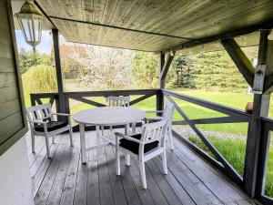 a table and chairs on a porch with a table at Uroczny domek z dużym ogrodem i tarasem blisko jeziora, cisza i spokój in Omin