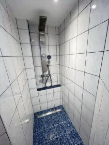 a white tiled bathroom with a shower with a mirror at Ferienwohnung Rhön mit Terrasse im Grünen in Burkardroth +2 photos