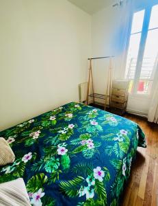 a bedroom with a bed with a blue blanket with flowers at Havre de Paix 10 mn Centre Paris in Clichy
