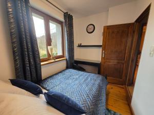 een slaapkamer met een bed en een raam en een klok bij Gniazdko Czarodzieja in Jedlina-Zdrój