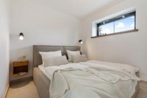 une chambre avec un lit avec des draps blancs et une fenêtre dans l'établissement Luxus-Ferienwohnung DS11, à Fehmarn