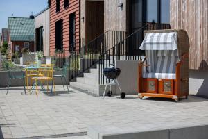 un patio avec des chaises et un barbecue et une table et des chaises dans l'établissement Luxus-Ferienwohnung DS11, à Fehmarn