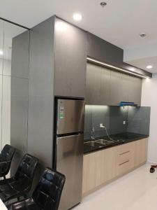 a kitchen with a stainless steel refrigerator and two chairs at The Emerald Golf View in Thuan An