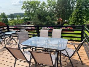 a glass table and chairs on a deck with flowers at Gospodarstwo Agroturystyczne Marzena in Kętrzyn