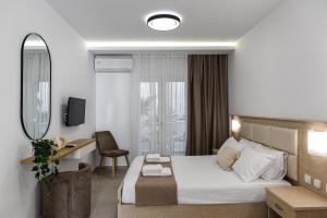 een hotelkamer met een bed, een bureau en een spiegel bij Porto Psakoudia in Psakoudia