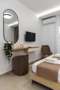een slaapkamer met een bed, een spiegel en een stoel bij Porto Psakoudia in Psakoudia