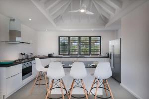 Petit Cul de SacにあるHilltop Deluxe Villa in Petit Cul De Sacのキッチン(白い家電製品、白いスツール付)