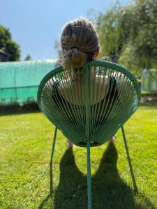 a woman sitting on a green chair in the grass at Arduinna's Nest B&B in Neufchâteau