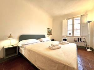 锡耶纳Pellegrini- Behind the Cathedral的卧室里有一张白色的大床，床上放着毛巾