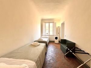 锡耶纳Pellegrini- Behind the Cathedral的有三张床和一扇窗户的房间